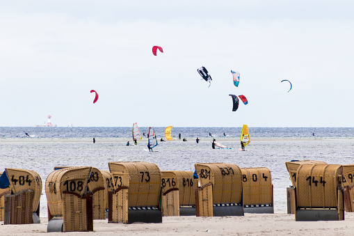 A big crowd of wind and kite surfers at the Baltic Sea near Laboe in Germany with wicker beach chairs in the foreground. Royalty free stock photo.