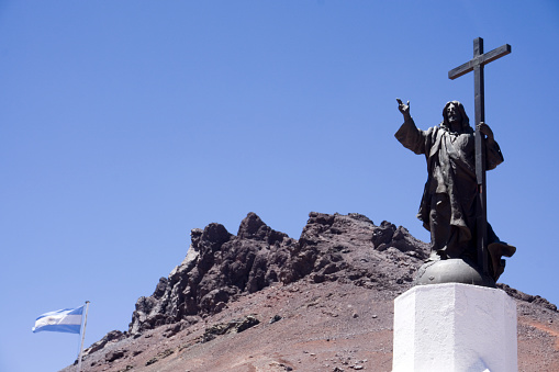 monument to Christ the Redeemer of the Andes with mast with Argentine flag on one side, in Mendoza, border between Argentina and Chile