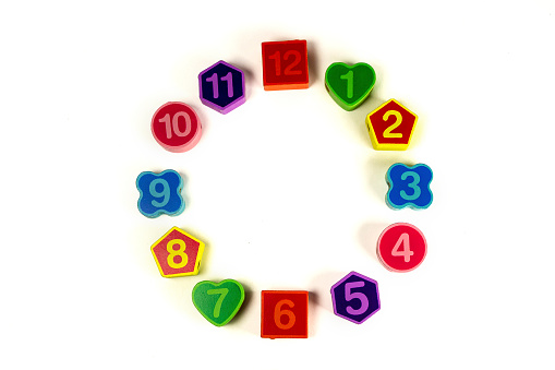 Colorful bright educational toys in the form of lacing for children.Educational toys. Colorful wooden geometric shapes pattern with numbers on white background. Copy Space Imitation clock.