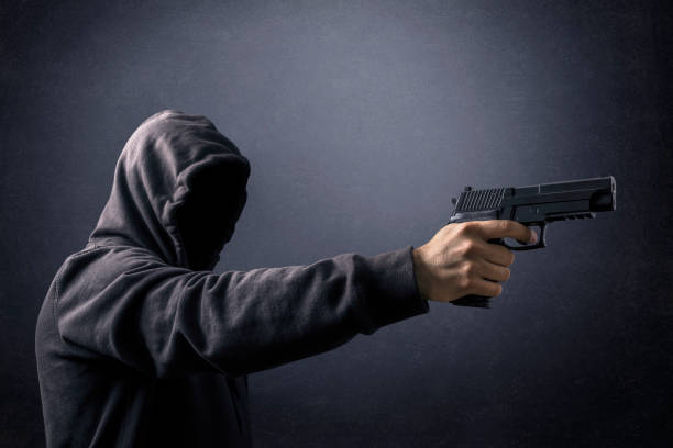 istock Hooded man with a gun in the dark 1264835539