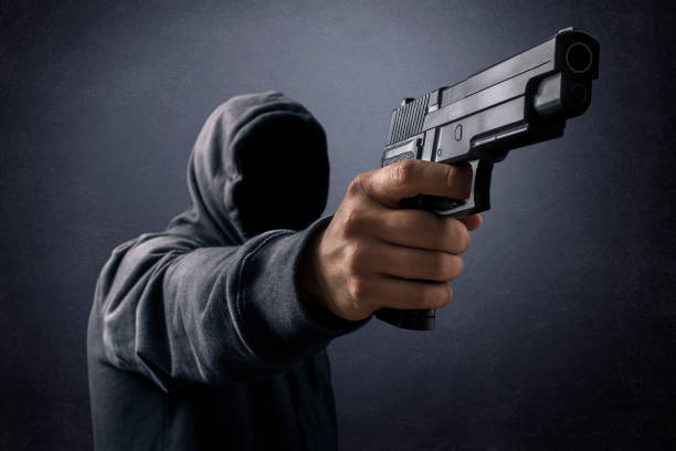 istock Hooded man with a gun in the dark 1264835564