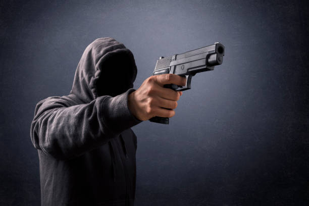 istock Hooded man with a gun in the dark 1264835593