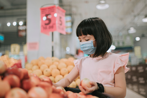 an asian chinese young girl buying fruit in supermarket duriing weekend looking at the fruit