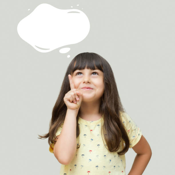 Cute little girl looking up she points finger up to a speech bubble, Copy space Cute little girl looking up she points finger up to a speech bubble, Copy space elementary student pointing stock pictures, royalty-free photos & images