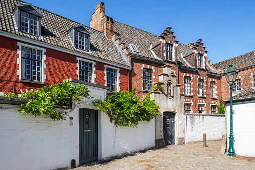 Ghent, Belgium - August 22, 2019: Alley with red houses in the small beguinage O.L.V. Ter Hooyen / Our Lady of Hooie / Our-Lady Ter Hooyen in the city Ghent, East Flanders, Belgium