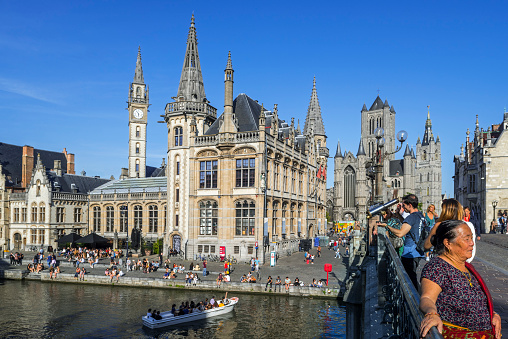 Ghent, Belgium - August 22, 2019: Sightseeing boat with tourists on the river Lys with view over guildhalls at the Graslei / Grass Lane in the city Ghent / Gent, East Flanders, Belgium