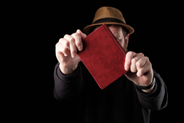 istock a white bearded man in a hat holds a book in front of him with both hands, defends himself like a shield 1264841745