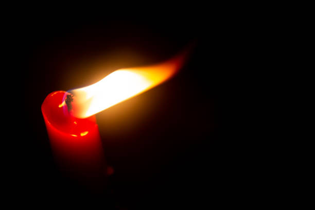 istock Red candle with yellow flame on black background 1264842105