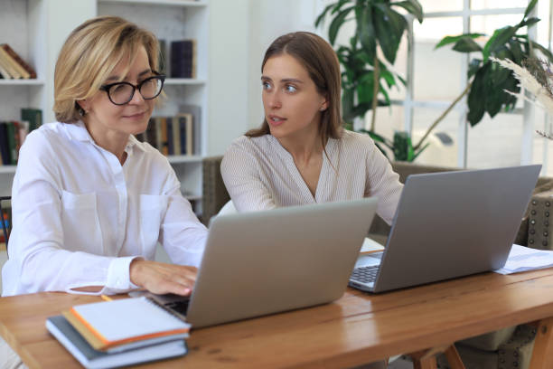 istock Two female collegues working with laptop and discussing new project. 1264845464