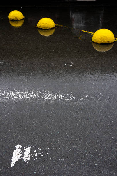 istock Yellow concrete hemispheres on wet asphalt. 1264845677