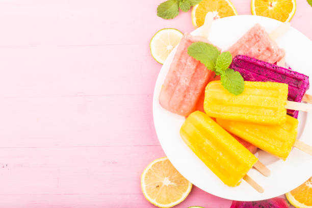 Various fresh fruit popsicles placed on wooden board background