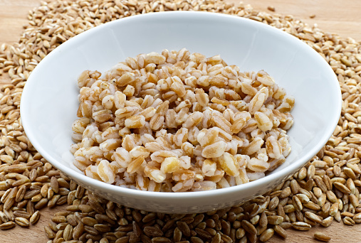 Boiled spelt in a bowl isolated on wooden background