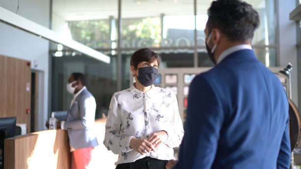 istock Coworkers talking on office's lobby - with face mask 1264853208