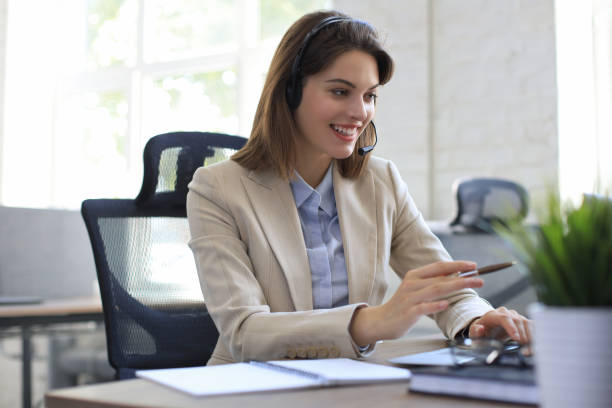 istock Beautiful smiling call center worker in headphones is working at modern office 1264862520