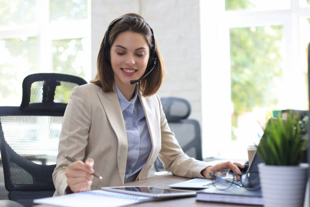istock Beautiful smiling call center worker in headphones is working at modern office 1264862586