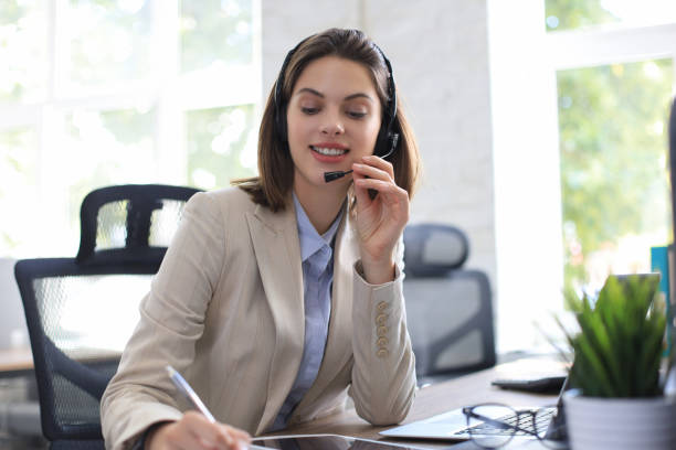 istock Cheerful female manager sitting at office desk and performing corporate tasks using wireless connection on digital gadgets. 1264862595