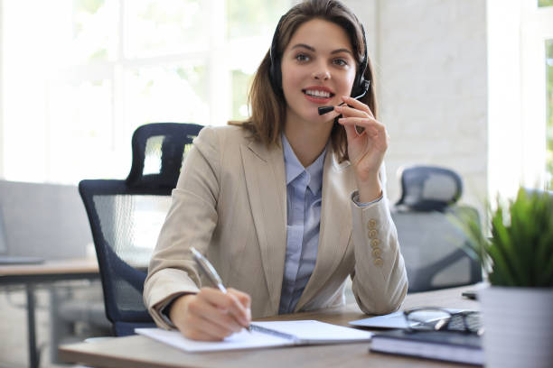istock Beautiful smiling call center worker in headphones is working at modern office 1264863689