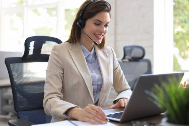 istock Beautiful smiling call center worker in headphones is working at modern office 1264863711