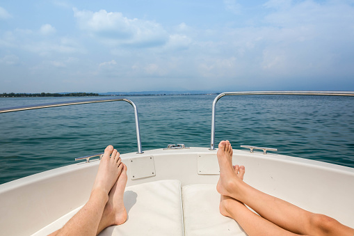 two pairs of feet, lake Garda, blue water, white boat, Italy, relaxing