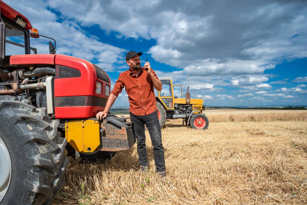istock Farmer controlled harvest in his field and talking on a smart phone 1264865018