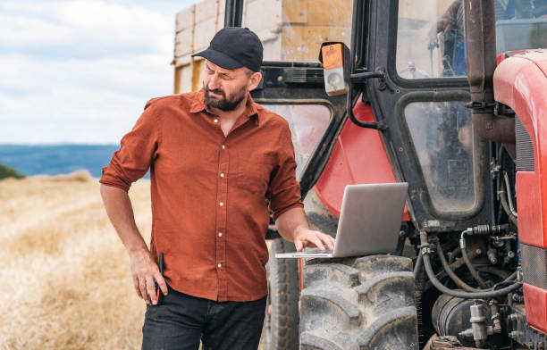 istock Farmer controlled harvest in his field and using laptop 1264865030