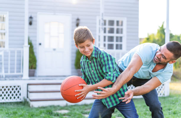 istock Father And Son Playing Basketball in front of front yard 1264865804