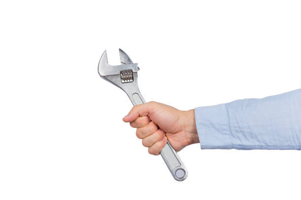 The hand of a mature man holding a crescent wrench. Silver metal hand tool.