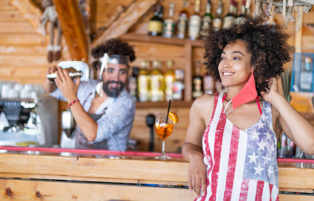 istock Bartender wears face shield and prepares cocktails for customers, during COVID-19 1264872746
