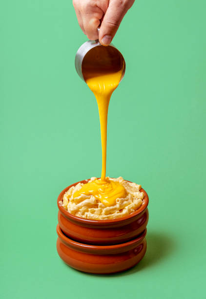 istock Macaroni and cheese making of. Pouring melted cheddar cheese over pasta. 1264872955
