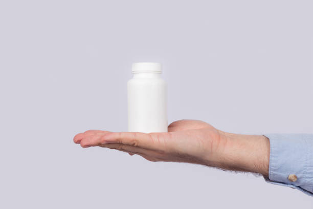istock White plastic container for pills on palm on white background. Copy space. Template. Mockup 1264873839