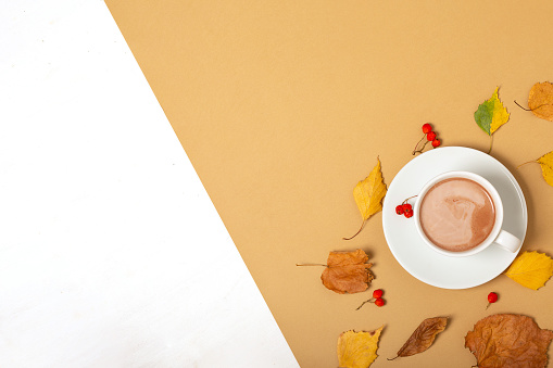 Cup of coffee, dried leaves on a beige background. Autumn, fall concept. Flat lay, top view, copy space. Autumn composition.