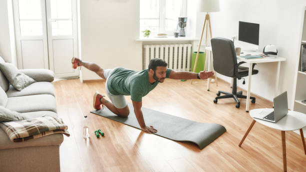 istock Workout indoors. Male fitness instructor showing exercises while streaming, broadcasting video lesson on training at home using laptop. Sport, online gym concept 1264885008