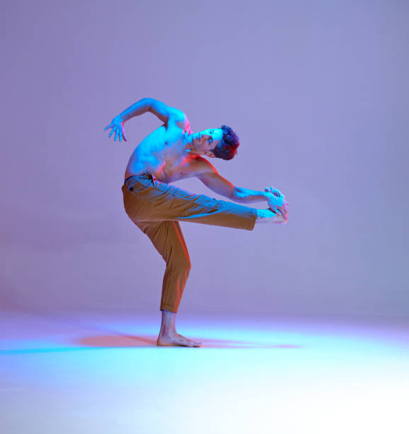 istock Cool young guy dancer dancing without shirt in neon lilac light. Colorful dance school poster 1264887518