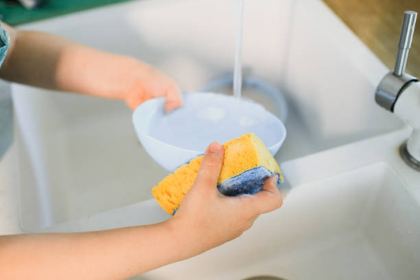 istock a little boy washes dishes in a modern kitchen 1264888975