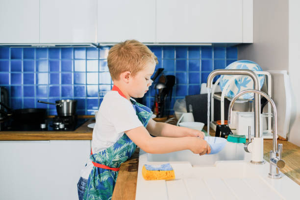 istock a little boy washes dishes in a modern kitchen 1264889010