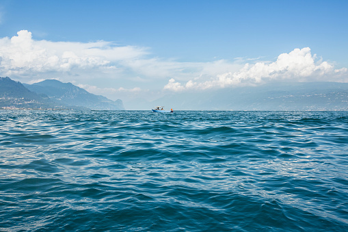 sea view with a speedboat on blue water and mountains, lake Garda, Italy