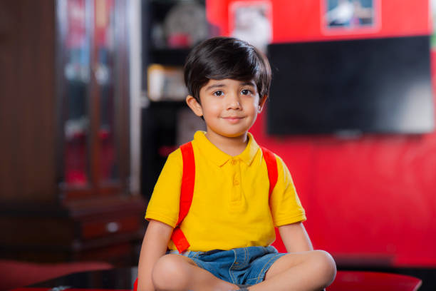An elementary aged boy takes a break from reading in the library to smile at the camera.
