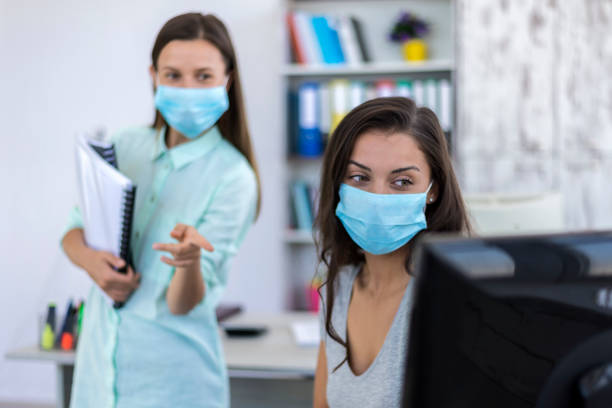 istock Two women in medical protective masks working in office. 1264913349