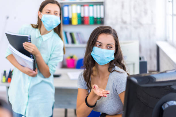 istock Two women in medical protective masks working in office. 1264913353