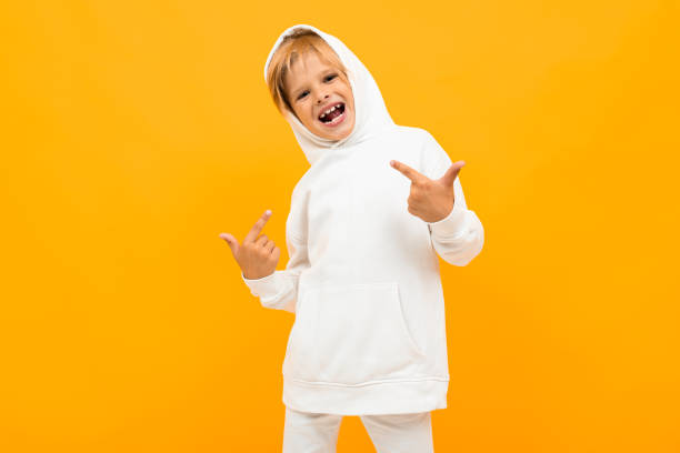 istock attractive blond boy in a white sweater is grimacing on an yellow background 1264914309