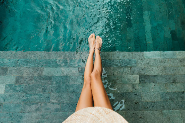primo piano di belle gambe femminili in acqua di una piscina - natural pool foto e immagini stock