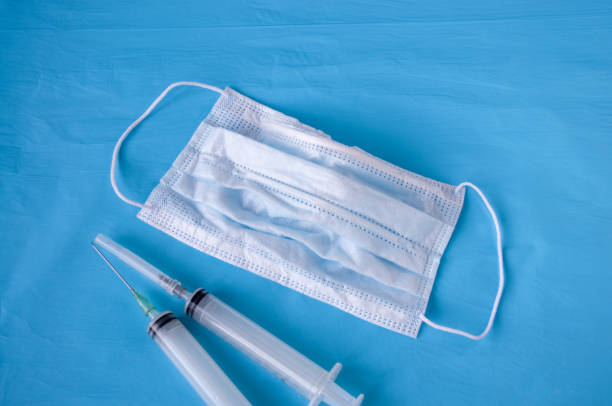 istock Medical white mask syringes on a blue background 1264927900