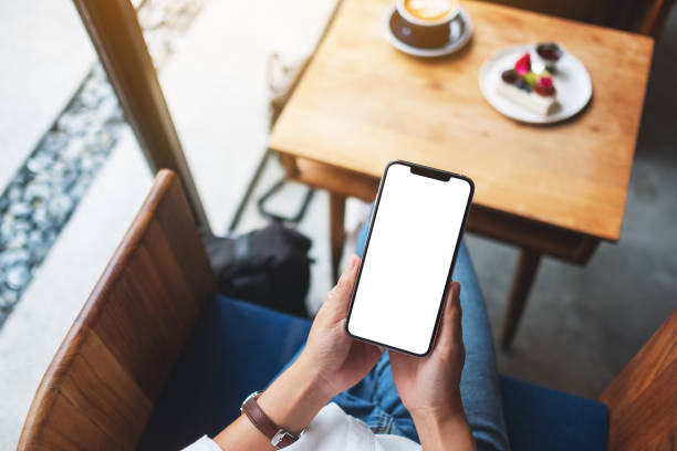 istock a woman holding mobile phone with blank white desktop screen in cafe 1264935034