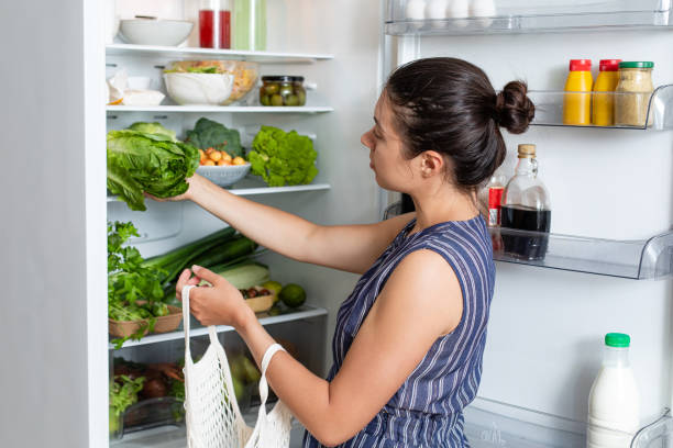 woman with eco bag puts vegetables in the refrigerator. grocery food basket. plastic free, zero waste, eco friendly concept. - vegies vegetable basket residential structure imagens e fotografias de stock