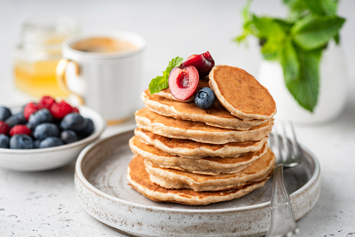 Healthy oat pancakes with berries on a craft ceramic plate. Vegan breakfast food