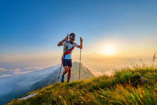 человек с полюсами в горах с закатом позади - jogging cross country running hiking outdoors стоковые фото и изображения