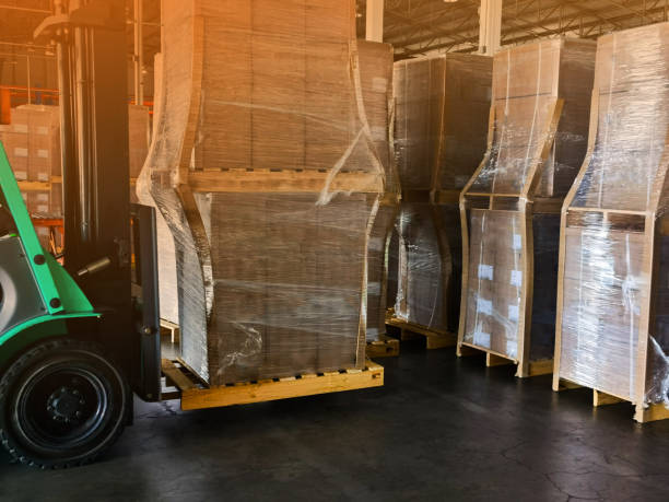 istock Worker driving forklift loading and unloading shipment carton boxes and goods on wooden pallet from container truck to warehouse cargo storage in logistics and transportation industrial 1264940975