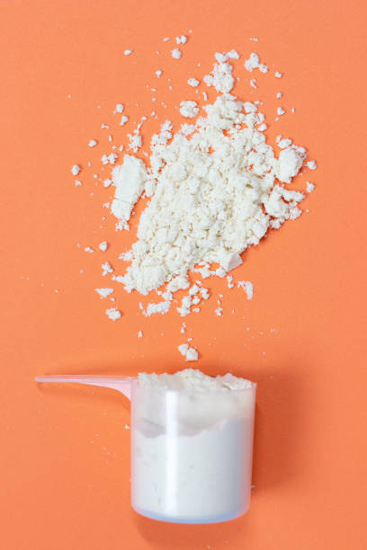 istock Measuring spoon with scattered protein powder on a orange background 1264952191