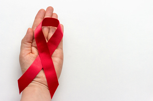 A woman's hand holds a red ribbon, the international day against AIDS and hiv in December