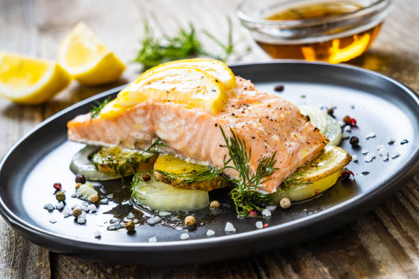 filete de salmón asado servido con limón y cebolla sobre mesa de madera - plato principal fotografías e imágenes de stock